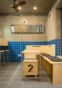 Bathroom with metal divider separating two sink areas, blue tiles, and a mirror above one sink