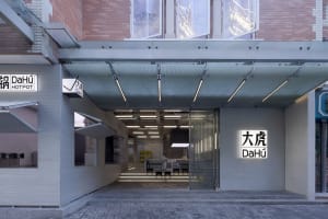 Open office space with glass door, modern furniture, and a mounted TV, filled with chairs and tables in a bright and inviting atmosphere