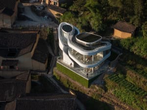 A modern house with a curved roof and multiple levels, featuring large windows and a concrete exterior