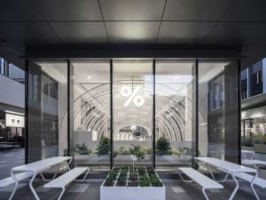 A bright and open interior space with a large glass wall, potted plants, and benches, showcasing a modern and inviting atmosphere