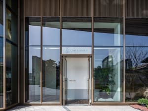 Welcoming entrance with a glass door, metal frame, and two potted plants adding a touch of greenery to the scene