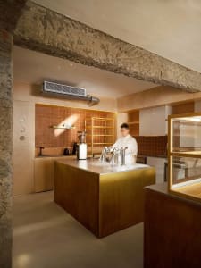 A well-equipped kitchen with a wooden theme, featuring a countertop with various items, two sinks, a refrigerator, and a microwave