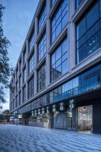 A large commercial building with a modern design, featuring glass panels and many windows on its facade, allowing natural light to enter the interior spaces
