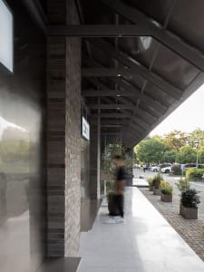 A calm and inviting exterior scene featuring a brick wall, a glass door, and potted plants surrounding the area