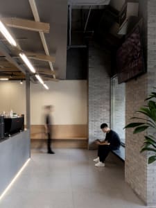 A relaxed restaurant and living area with a bench, potted plant, dining table, and chairs, featuring wood and stone materials