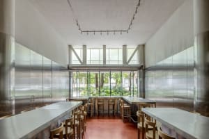 A well-lit restaurant interior with a large dining table surrounded by multiple wooden chairs, perfect for a relaxed meal