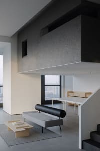 Open modern living area with a couch, chairs, dining table, and bench, surrounded by natural light and minimal decor