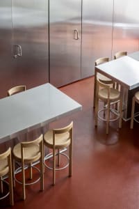 Industrial dining space with a metal table and wooden chairs, well-lit with natural light or overhead lighting