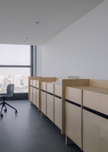 Office space with two desks, chairs, and cabinets, offering a view of the city outside through a large window
