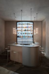 A social bar area with a display of liquor bottles, wooden chairs, and a welcoming atmosphere