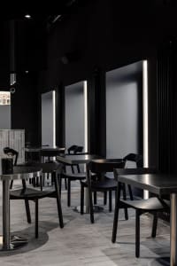 Sophisticated restaurant interior with black tables and chairs, multiple dining tables, and a modern atmosphere