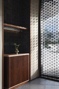 A wooden cabinet with a potted plant on top, surrounded by vases and a view of a car through a window