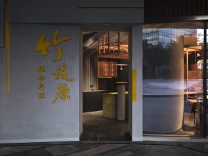 A modern Asian restaurant with a large window, two dining tables, and a vase, creating an inviting and comfortable atmosphere