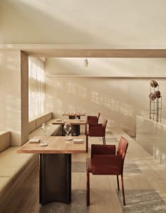 Empty restaurant interior with wooden floors, white walls, and dining tables set with wine glasses and tableware