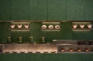 A clean and organized kitchen with green walls and a countertop featuring variously sized bowls and two cups, emphasizing functionality and practicality