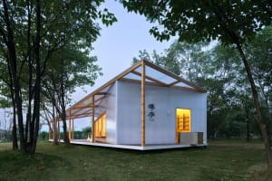Asian-style house with a wooden structure and a white exterior, featuring a large window and a peaceful atmosphere