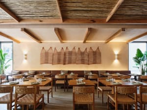 Warm and inviting restaurant interior with wooden tables and chairs, woven wall hangings, and a comfortable atmosphere
