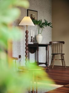 A warm and inviting living area with a wooden floor, two chairs, a dining table, a potted plant, and a vase, featuring natural wood elements and comfortable seating arrangements