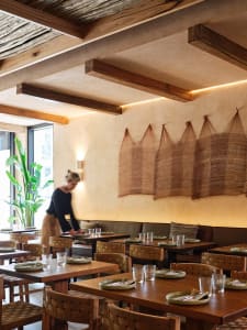 A warm and inviting restaurant interior with wooden tables and chairs arranged in rows, providing seating options for guests