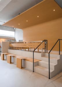 Warm and inviting lobby space with wooden floors and walls, featuring multiple benches for seating