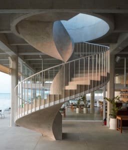 A rendered image of a spiral staircase with concrete steps, artificial lighting, and a dark atmosphere