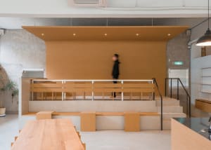 A calm and inviting lobby with wooden floors and walls, featuring benches and a person walking through the space