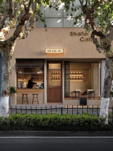 Cozy Asian restaurant with a wooden exterior and interior, featuring a dining area with chairs and a potted plant near the entrance