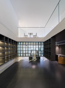 Open office space with glass walls, natural light, and various seating options, including chairs and a dining table