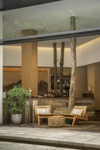 A well-lit living area with a wooden theme, featuring a large window, two chairs, and a dining table