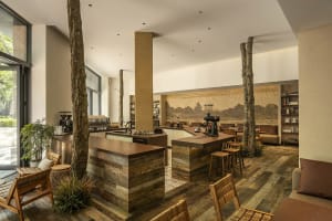 A warm and inviting cafe interior with wooden tables, chairs, and walls, featuring multiple dining tables and a cozy atmosphere