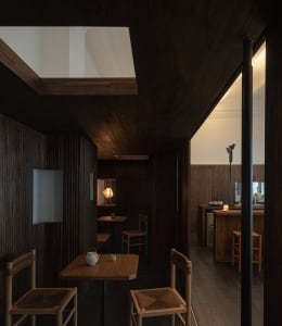Cozy restaurant interior with wooden floors and walls, featuring dining tables and chairs, and a warm atmosphere