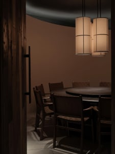 Dimly lit dining area with a round table surrounded by chairs, creating a cozy atmosphere