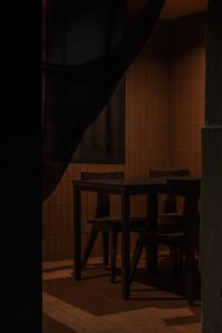A cozy dining space with a wooden table and chairs, surrounded by orange-tiled walls, creating a warm and inviting atmosphere