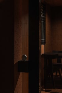 Dining space with a wooden table and chairs, a vase on the table, and warm wooden walls