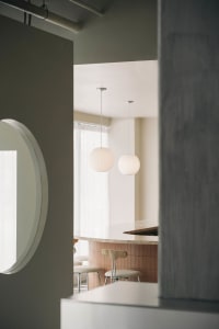 Modern living space with a bar counter, two chairs, two dining tables, and a couch, featuring a focus on functionality and comfort