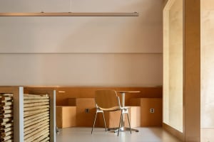 A simple restaurant dining area with a wooden table and chairs, surrounded by white walls and a clean atmosphere