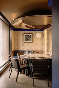 A formal dining area with a round table, chairs, and wine glasses, set for a sophisticated dinner