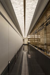 Bright and well-lit empty hallway with white walls and black floors, featuring two staircases leading to different levels