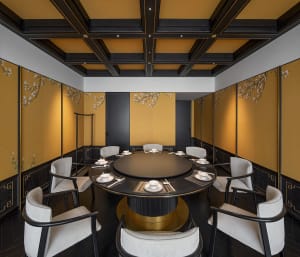 A warm and inviting Asian restaurant interior with a large dining table surrounded by chairs and plates of food, set for guests