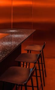 Warm and inviting orange kitchen with a countertop and three black chairs, creating a cozy seating area