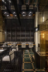 Sophisticated dining space with white tablecloths, black and gold walls, and comfortable seating for guests