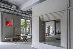 A modern industrial lobby with concrete walls, featuring chairs and dining tables, and a minimalist atmosphere