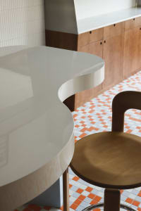a modern dining space with a wooden table and two chairs, featuring a clean and minimalist aesthetic