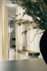 A wooden table with a silver base and lamp, surrounded by curtains in a cozy room for relaxation or dining