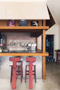 Cozy kitchen with a wooden countertop, red stools, and chairs, surrounded by books and a warm atmosphere
