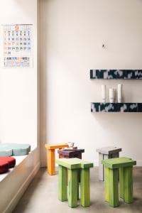 A modern office space with white walls, three chairs, two dining tables, and cups on one table