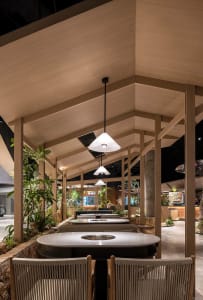 Dining area with wooden tables, chairs, and potted plants, creating a warm and inviting atmosphere