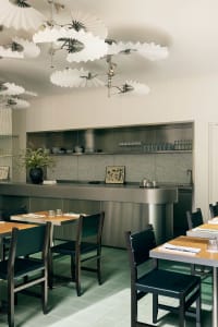 Modern kitchen and dining area with a large countertop island, multiple chairs, and dining tables, surrounded by bottles and showcasing a sleek aesthetic