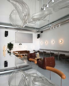 A well-lit dining area with multiple tables and chairs, varying in size and shape, set in a restaurant or cafe