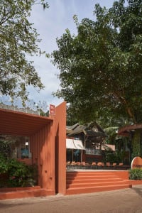 A restaurant with an orange building and a red door, featuring outdoor seating with chairs in various positions, creating a welcoming atmosphere for visitors